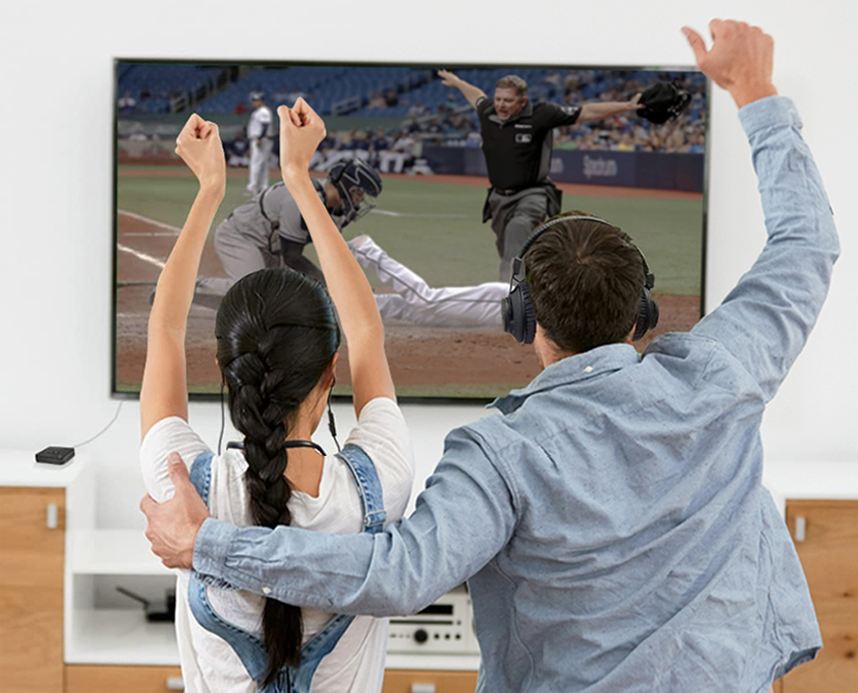 Couple facing TV watching baseball displaying that the Avantree D4169 does not have audio delay with an umpire saying 