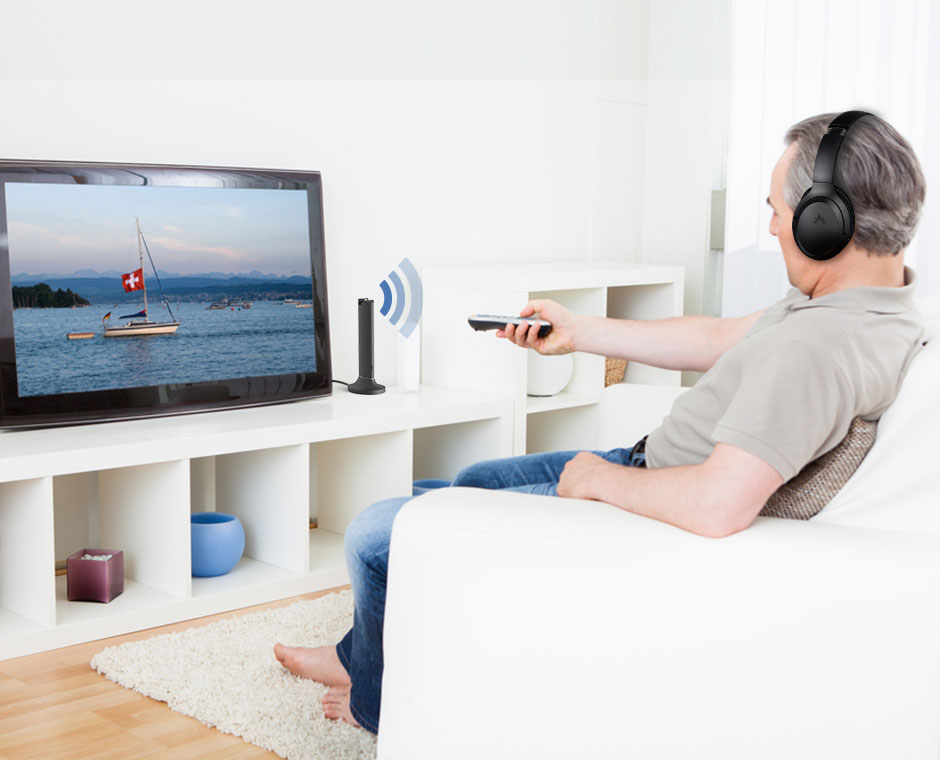 Man sitting on couch watching TV while wearing Opera Bluetooth v5.0 TV headphones and adapter set.